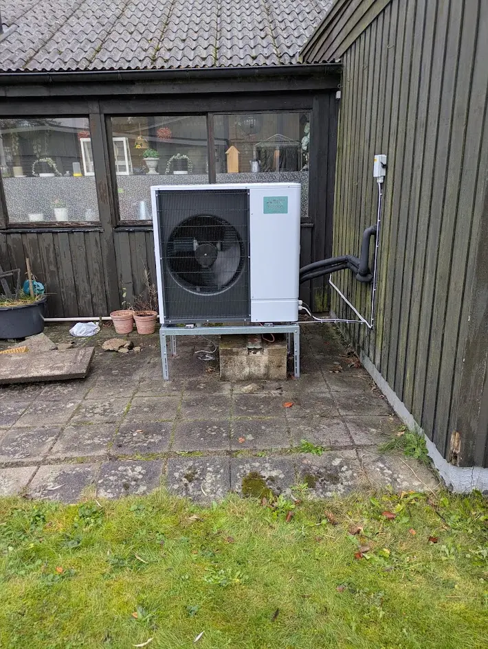 Värmepumpens utomhusenhet installerad vid träfasad